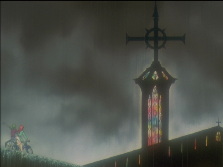 The church spire with stained glass and a rainy background.