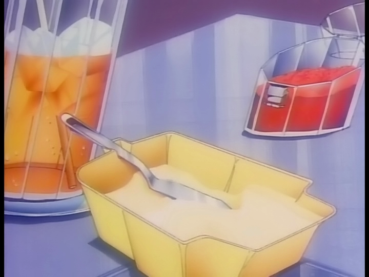 Breakfast items: An orange iced drink, a tub of butter, and a container of jam.
