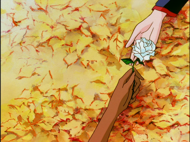 Anthy’s hand, reaching upward, places a white rose in Utena’s hand.
