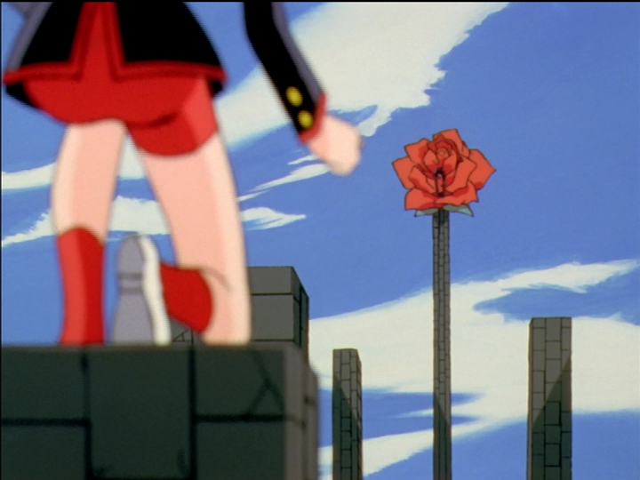 Columns rise from the dueling arena. Utena is on one in the foreground, Anthy’s show coffin on another in the background.
