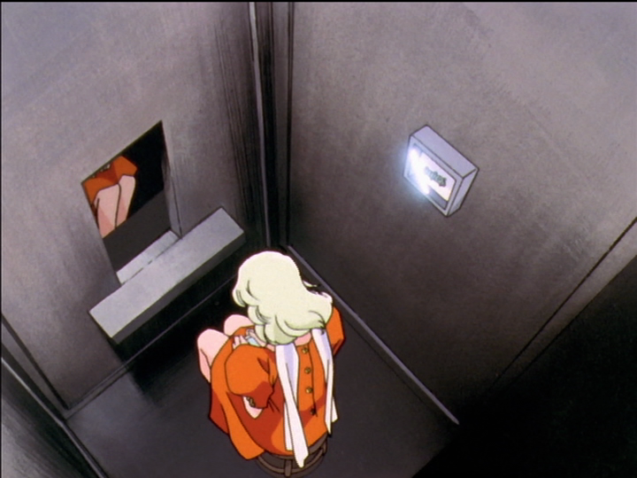 Kanae sits in the confession elevator. We see her from behind. Glass over the devolving butterfly in the confession elevator reflects white light.