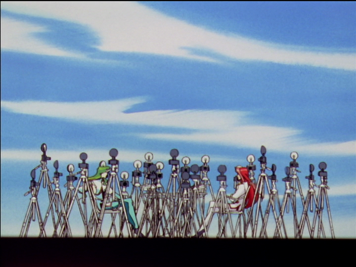 Saionji and Touga sit at a table, surrounded by cameras on tripods.